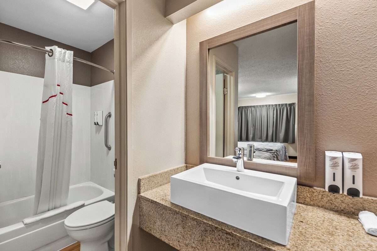 A bathroom with a shower, toilet, sink, and a mirror.