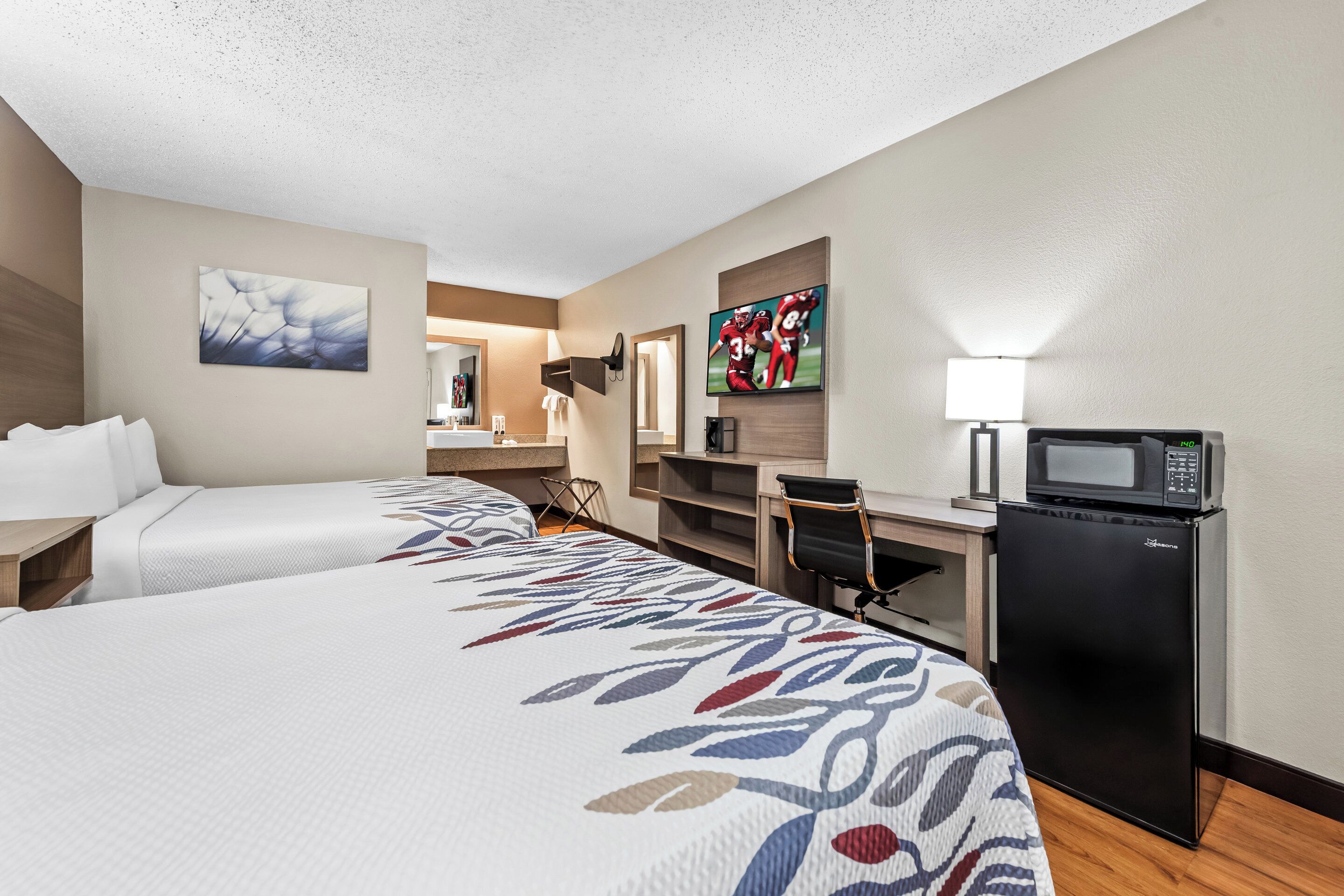 Une chambre d’hôtel avec deux lits, un bureau, un four à micro-ondes et une télévision.