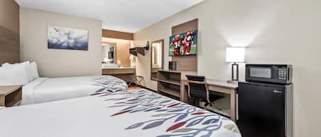 A hotel room with two beds, a desk, a microwave, and a TV.