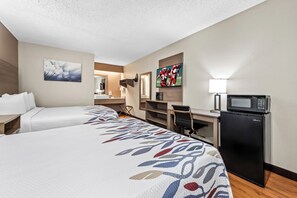 Une chambre d’hôtel avec deux lits, un bureau, un four à micro-ondes et une télévision.