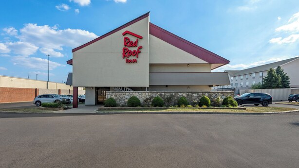 Un Red Roof Inn con un diseño moderno, que presenta un techo rojo destacado y una fachada de piedra.