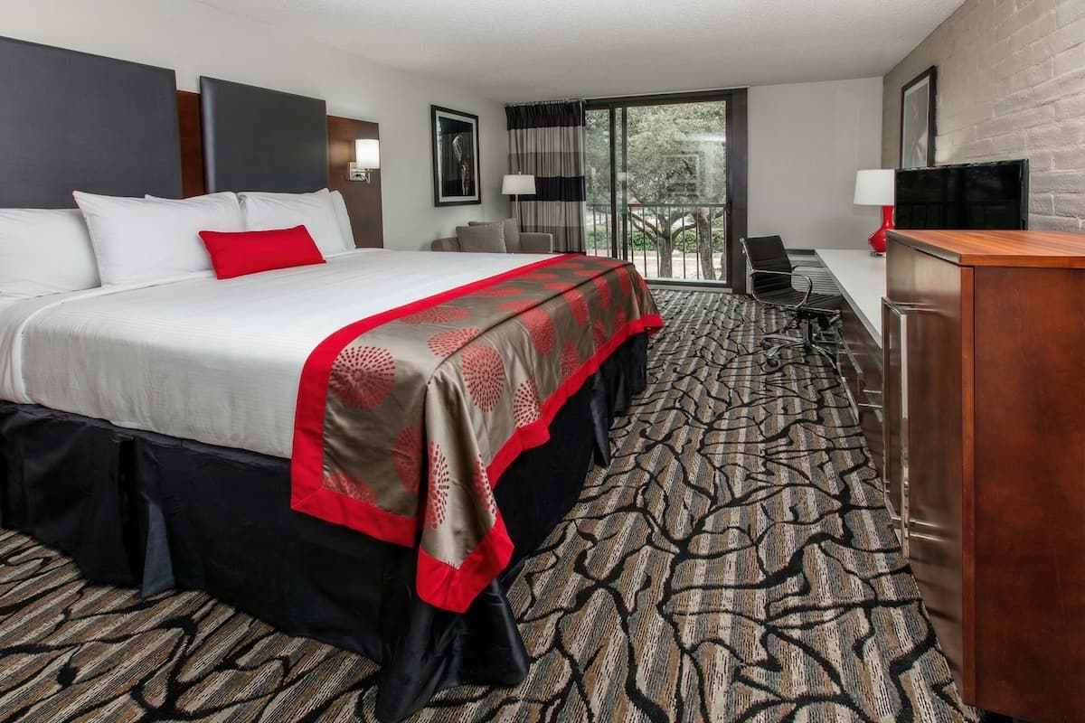 A hotel room with a large bed, a desk, a chair, and a television.