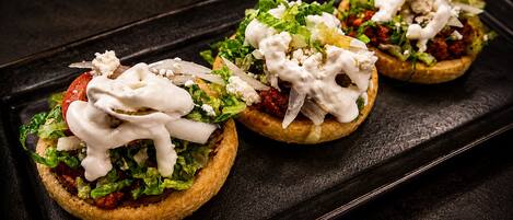 Tres sándwiches abiertos sobre una bandeja negra.