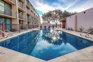 Una piscina al aire libre, sillones reclinables de piscina
