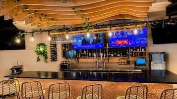 Un espace bar doté d’un long comptoir, de plusieurs téléviseurs et de tabourets de bar.