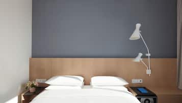 Habitación de hotel con cama, mesita de noche, lámpara y una pequeña planta.