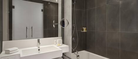 A modern bathroom with a white sink, mirror, and bathtub.