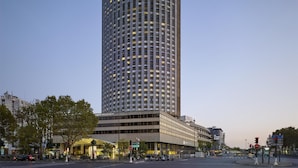 A tall, modern hotel with a curved facade and illuminated windows. - Hyatt Regency Paris Etoile (Paris)
