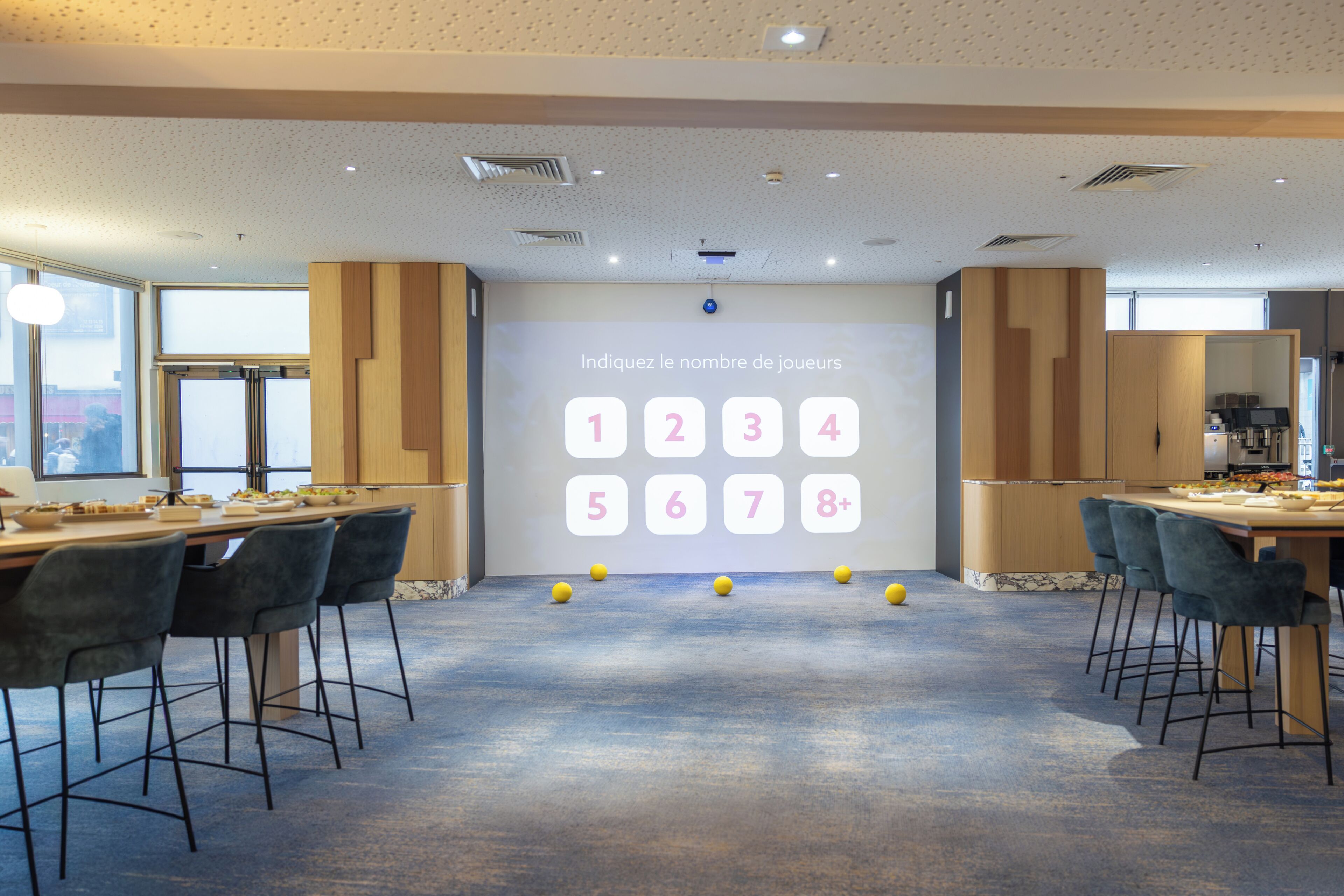 Una sala de conferencias moderna con una pared de visualización digital, varias mesas y sillas.