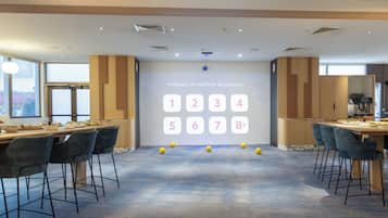 Una sala de conferencias moderna con una pared de visualización digital, varias mesas y sillas.