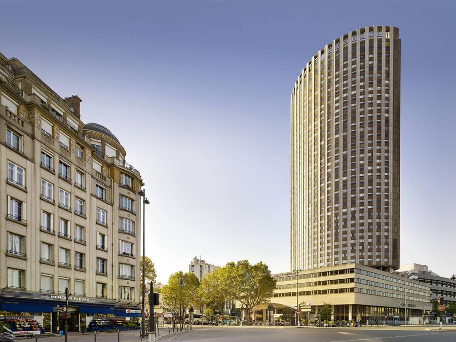Un hotel alto y moderno con fachada curva, situado en una intersección urbana.