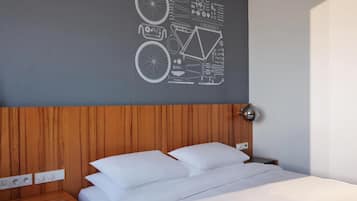 Una cama bien hecha con sábanas y almohadas blancas, un cabecero de madera y una pared con diseño geométrico.