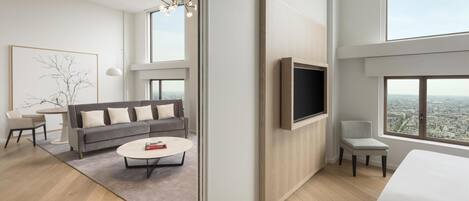 A modern living room with a grey sofa, a round coffee table, and a TV mounted on the wall.