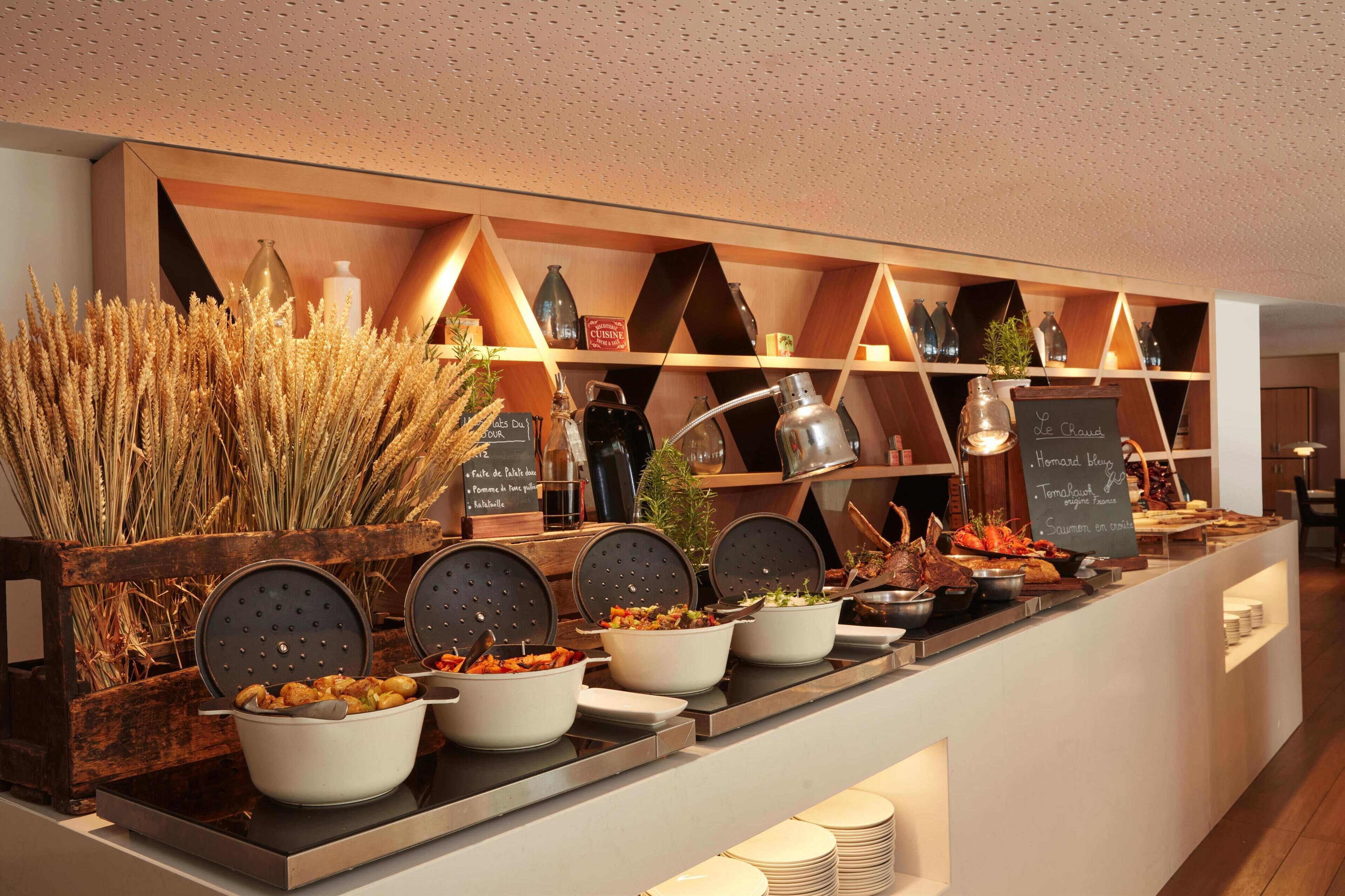 A buffet with various dishes and a decorative wall with shelves.