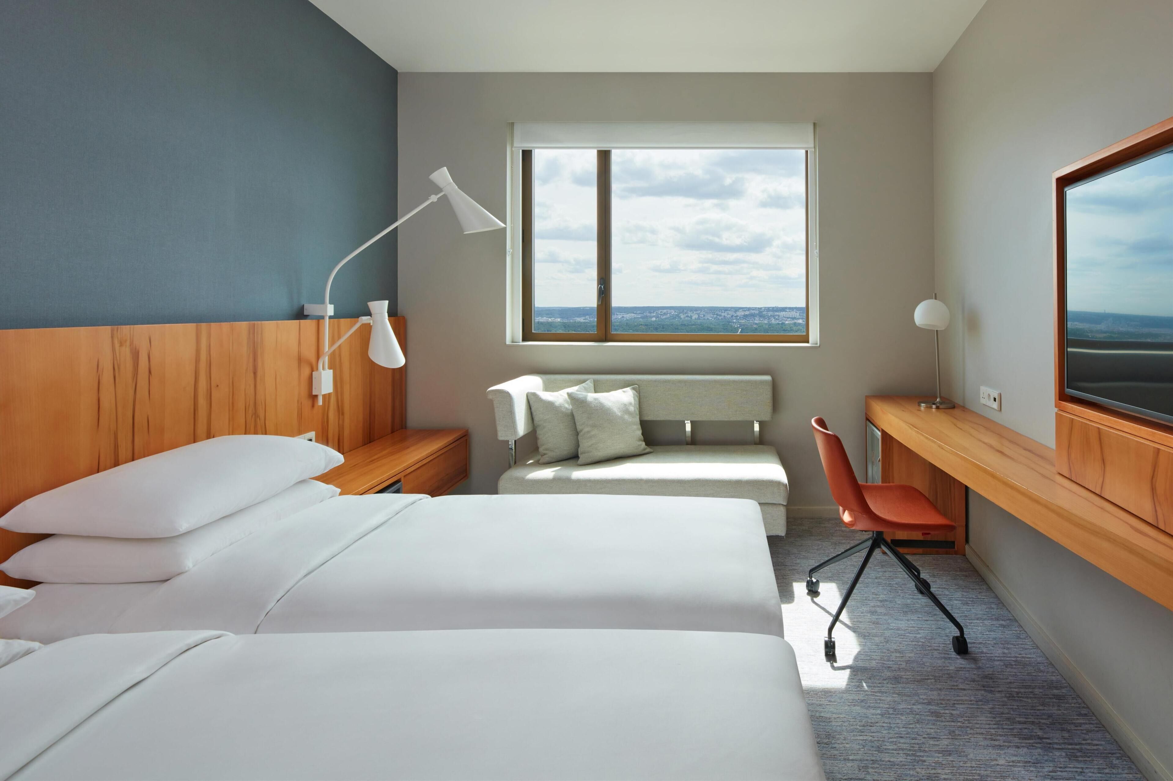Une chambre d’hôtel avec un grand lit, un bureau, une chaise et un téléviseur.