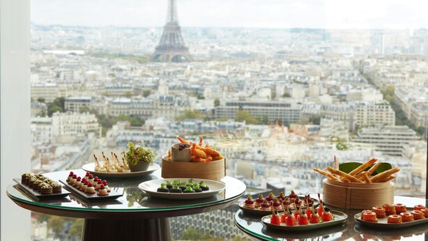 A table with various food items and a view of the Eiffel Tower in Paris. - Hyatt Regency Paris Etoile (Paris)