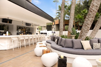 A modern living room with a leather sofa, a rattan chair, and unique wooden coffee tables. at Hotel La Jolla, Curio Collection by Hilton