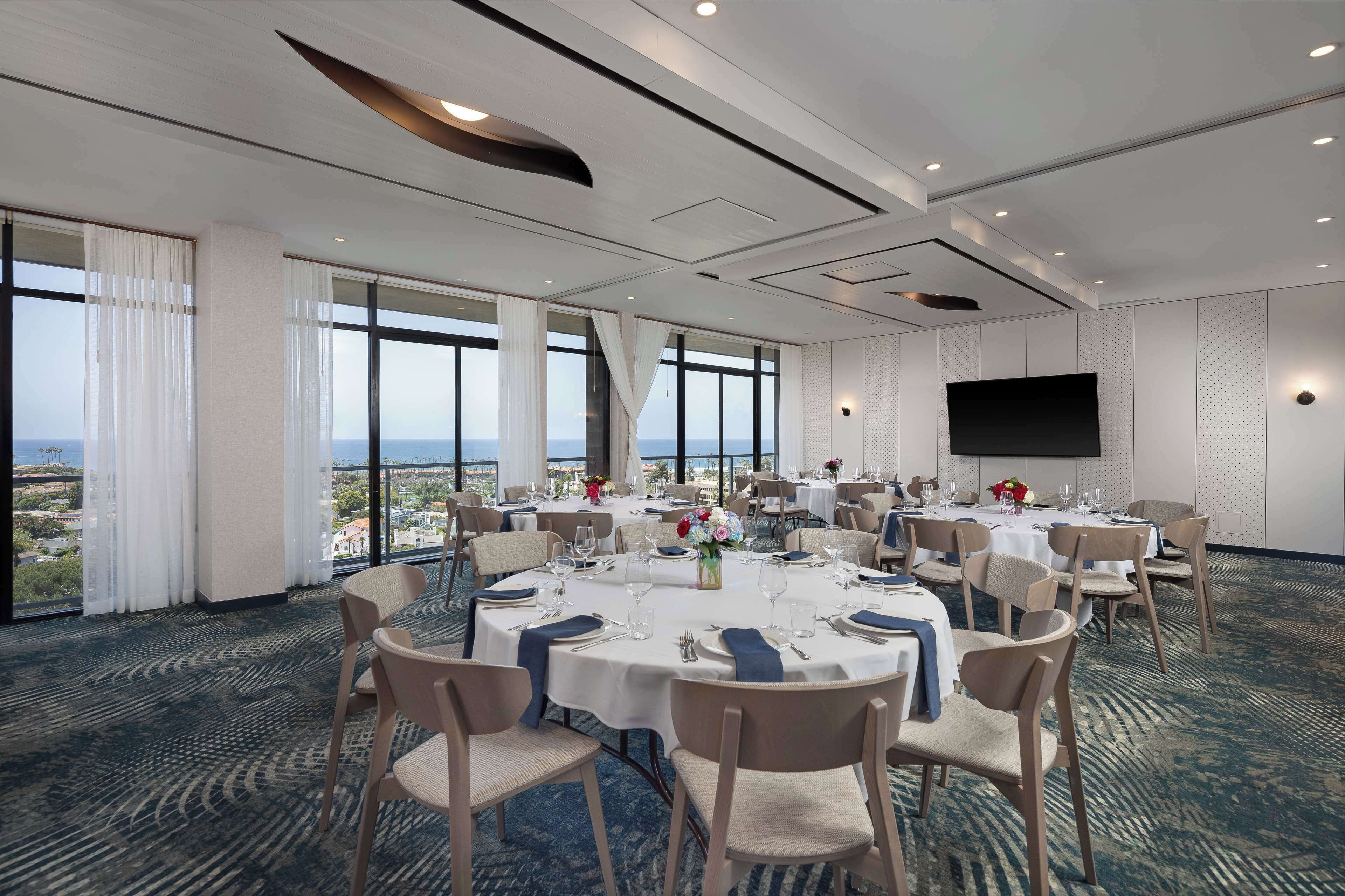 A conference room with round tables, chairs, and a large screen.