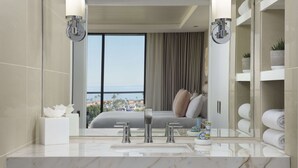 A modern bathroom with a large mirror, a marble countertop, and a view of a bedroom with a bed and a balcony. - Hotel La Jolla, Curio Collection by Hilton (La Jolla)