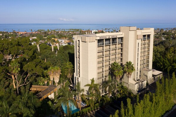 A high-rise hotel with a modern design, surrounded by lush greenery and a view of the ocean. - Hotel La Jolla, Curio Collection by Hilton (La Jolla)