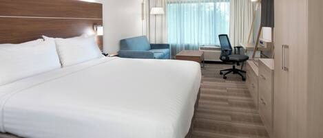 A hotel room with a large bed, a desk, a chair, and a mirror.