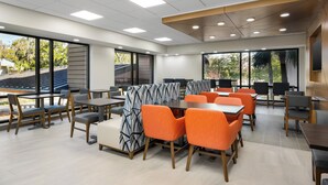 A modern dining area with tables and chairs, large windows, and a view of the outdoors. - Holiday Inn Express Hilton Head Island by IHG (Hilton Head Island)
