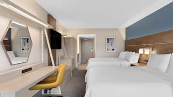 Een hotelkamer met een bureau, twee bedden, een televisie en een zichtbare badkamer door een geopende deur.