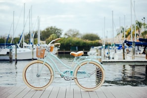 A vintage bicycle with a basket and seat, docked on a wooden pier with boats in the background. - Holiday Inn Express Hilton Head Island by IHG (Hilton Head Island)