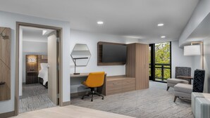 A modern hotel room with a wooden desk, a large mirror, a comfortable sofa, and a TV. - Holiday Inn Express Hilton Head Island by IHG (Hilton Head Island)