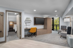 Une chambre d’hôtel moderne avec un bureau en bois, un grand miroir, un canapé confortable et une télévision.