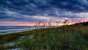 A coastal landscape with a beach, grassy dunes, and a sunset over the horizon. - Holiday Inn Express Hilton Head Island by IHG (Hilton Head Island)