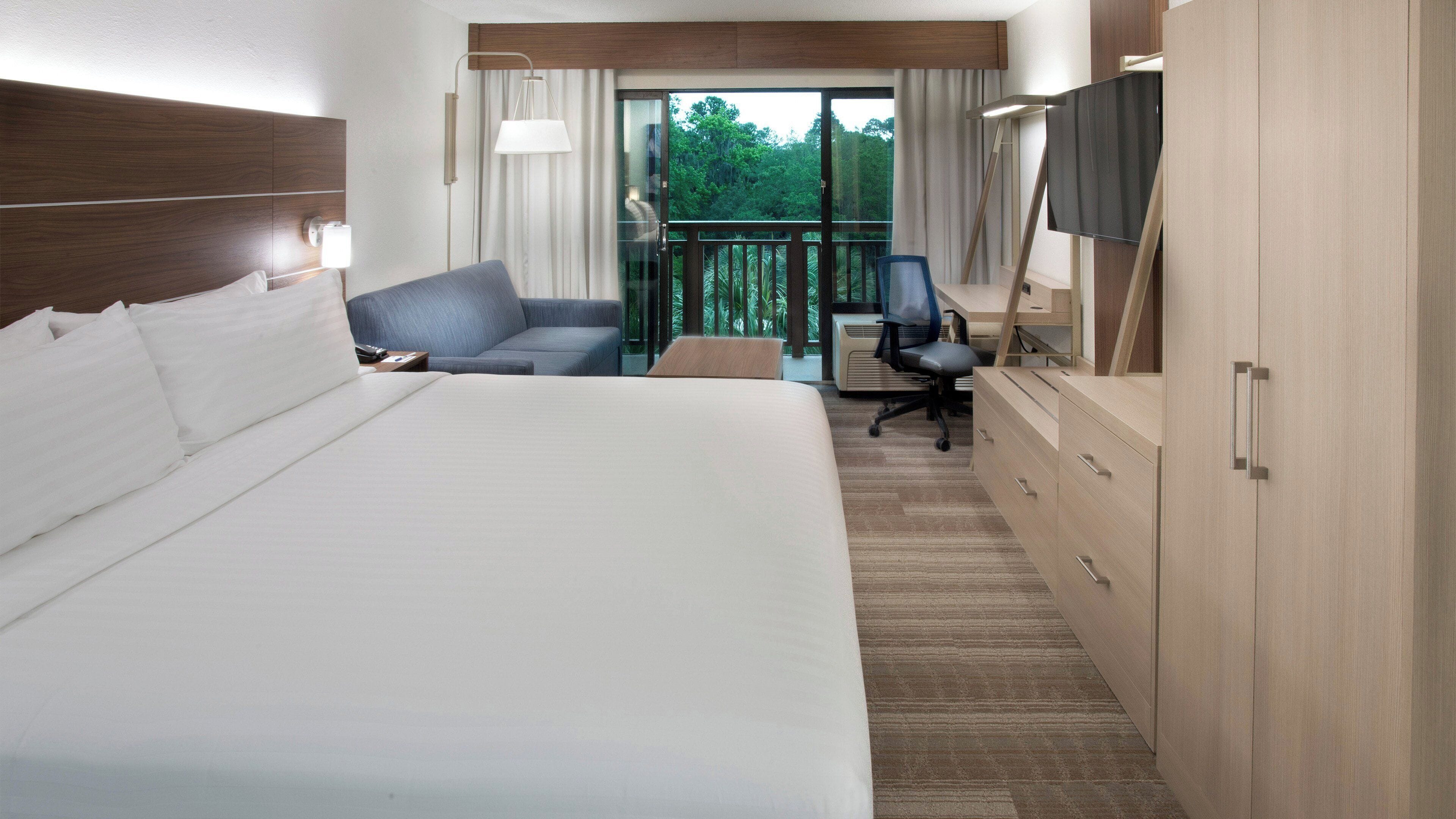 Una habitación de hotel con una cama grande, un escritorio, una silla y un televisor.