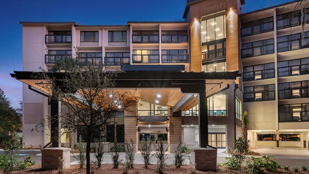 A multi-story hotel with a covered entrance, large windows, and a landscaped outdoor area. - Holiday Inn Express Hilton Head Island by IHG (Hilton Head Island)