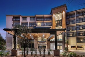 A multi-story hotel with a covered entrance, large windows, and a landscaped outdoor area. - Holiday Inn Express Hilton Head Island by IHG (Hilton Head Island)