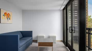 A modern living room with a blue sofa, a wooden coffee table, and a glass door leading to an outdoor area.