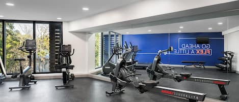 A gym with cardio equipment, weight machines, and a mirror wall.