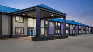 A modern hotel with a covered entrance, large windows, and a blue roof.