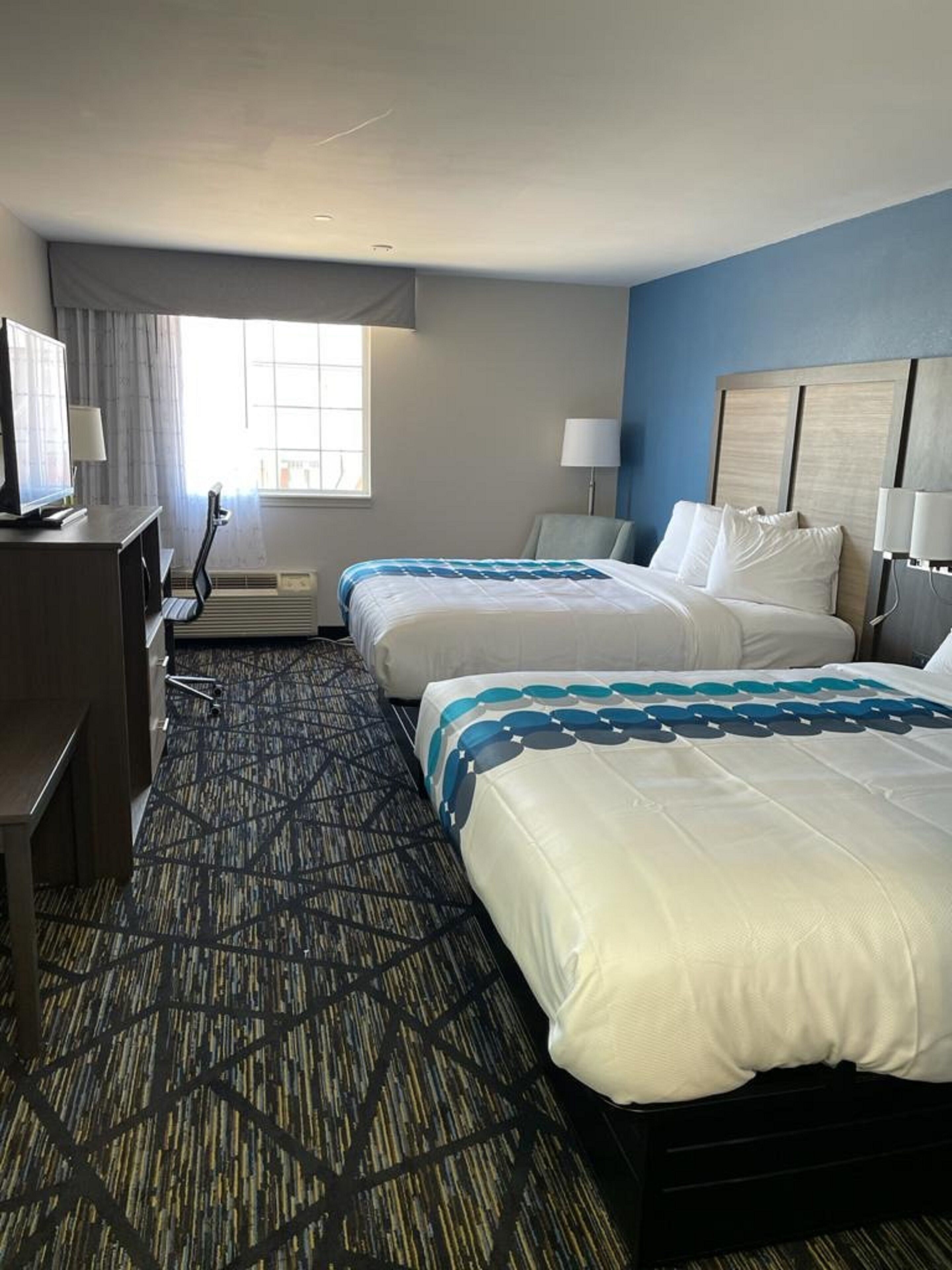 Une chambre d’hôtel avec deux lits, un bureau, une télévision et une fenêtre.