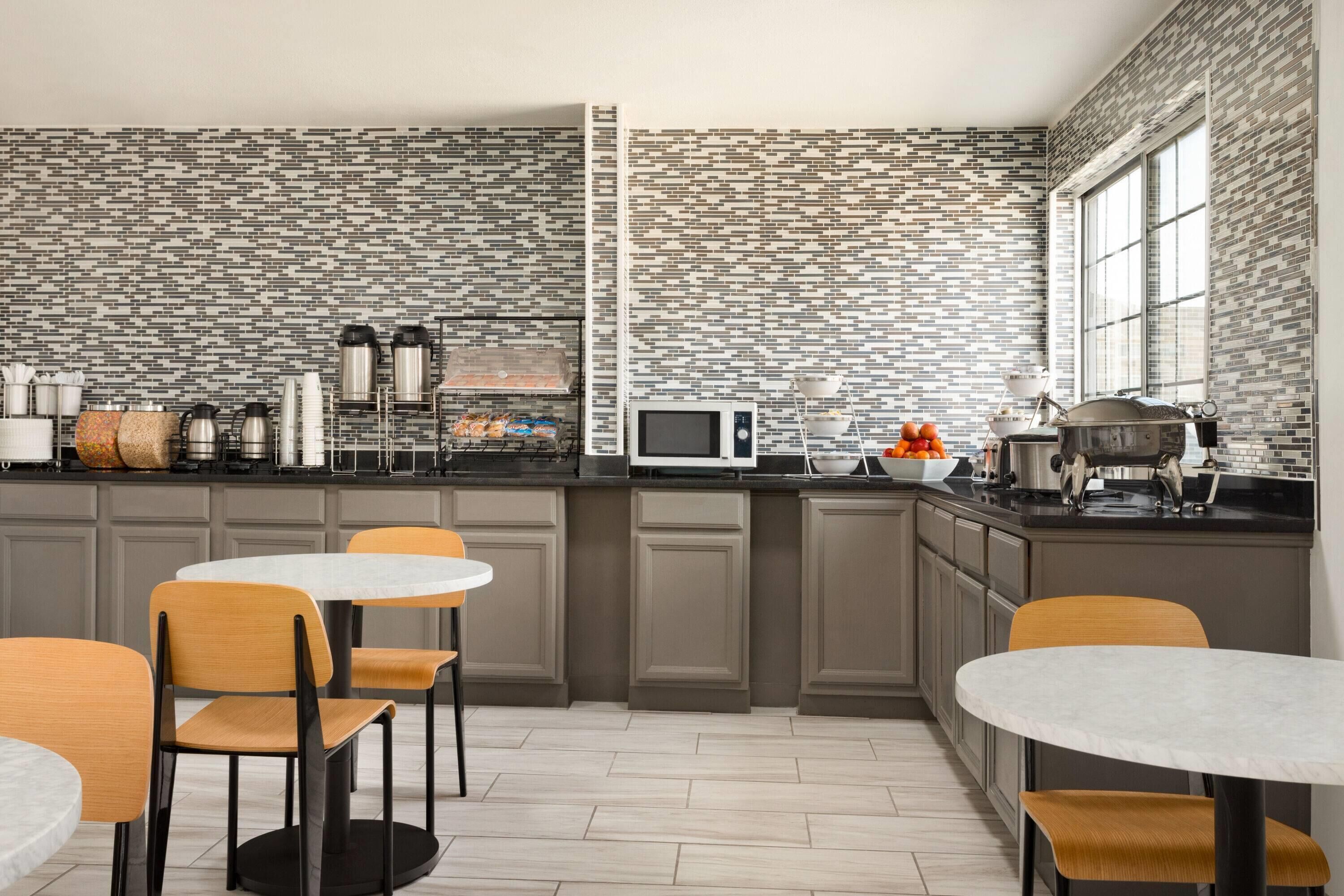 A modern kitchen with a tiled backsplash, built-in appliances, and a central island with seating.