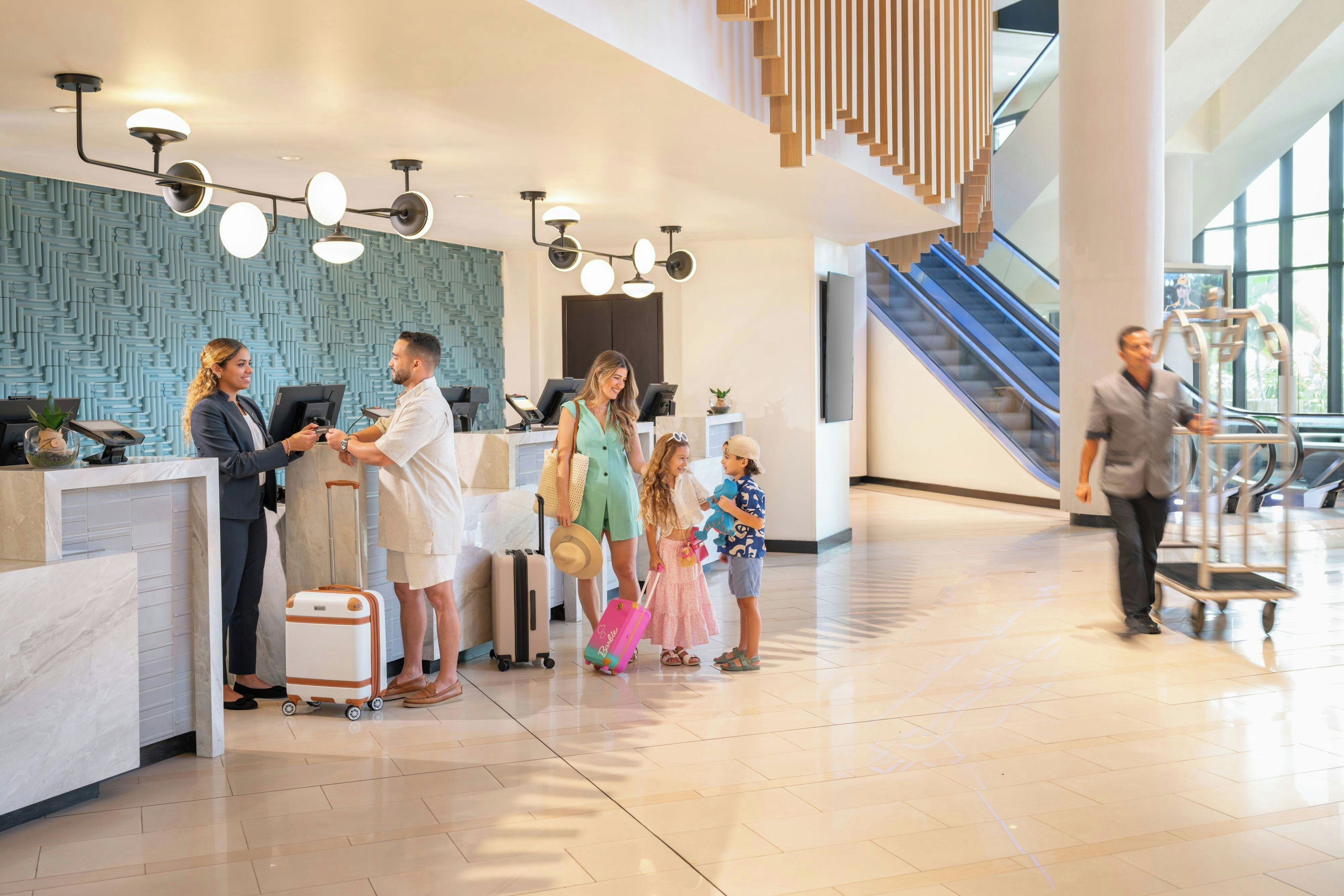 A hotel reception area with a modern design, including a marble counter, a patterned wall, and a staircase in the background.