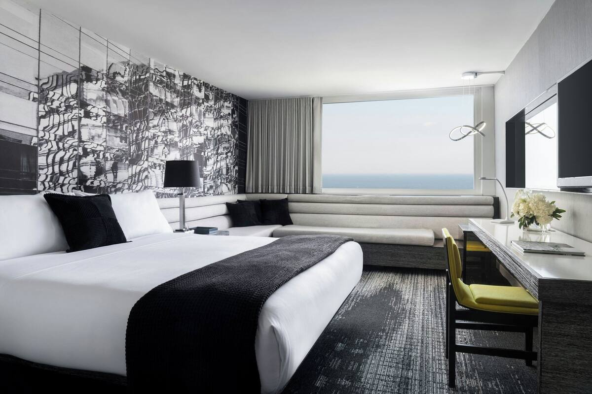 Une chambre d’hôtel moderne avec un grand lit, un bureau et une vue sur l’océan.