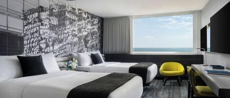 A hotel room with two beds, a desk, a chair, a large window with a view, and a modern wall design.