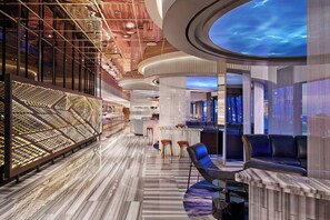 A modern hotel lobby with a marble floor, a seating area with a bar, and a unique ceiling design. - The Wade (Chicago)