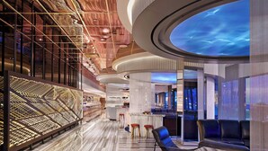 A modern hotel lobby with a marble floor, seating areas, and a ceiling with a sky-like projection. - The Wade (Chicago)