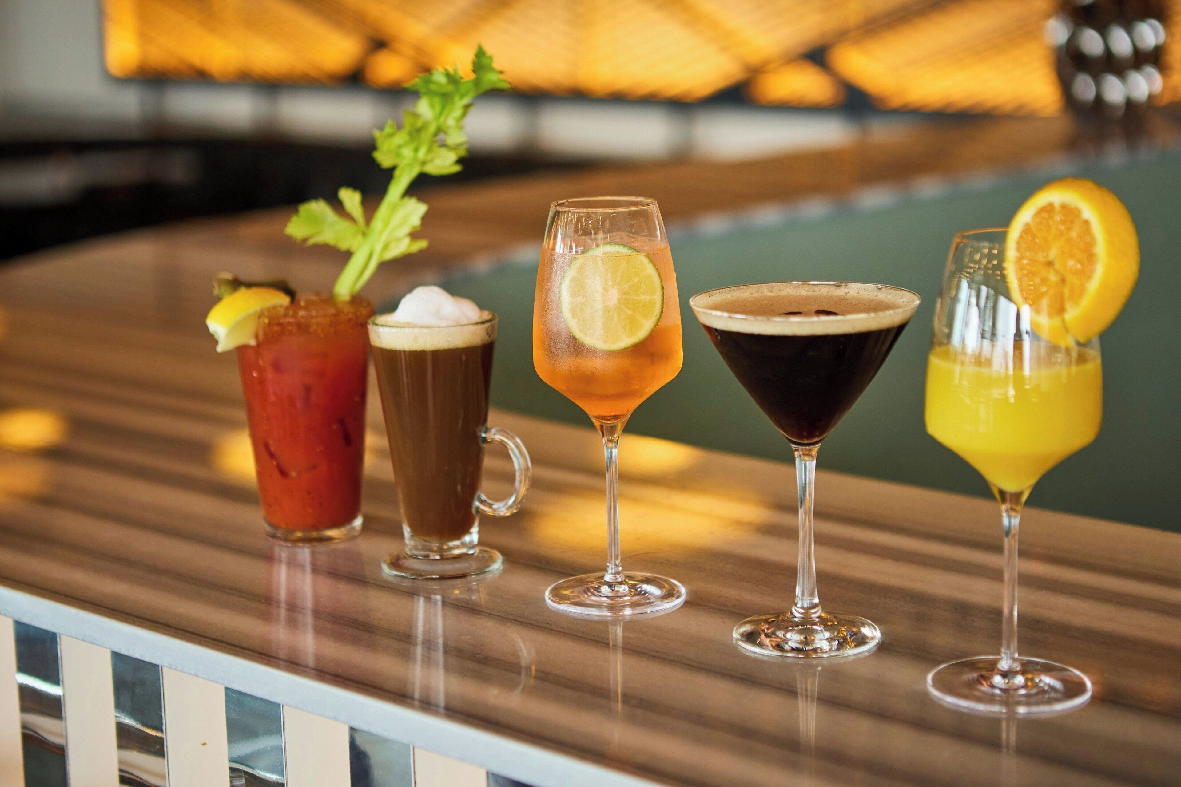 Una barra con cuatro bebidas distintas, cada una decorada con una rodaja de fruta.