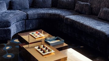 A modern living room with a sectional sofa, a coffee table with food, and a blue box.