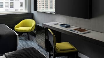 Een moderne hotelkamer met een bed, een bureau, een stoel en een televisie aan de muur.