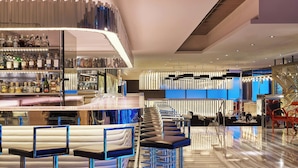 Uma área de bar moderna com banquetas altas, balcão e prateleiras com garrafas de bebidas.