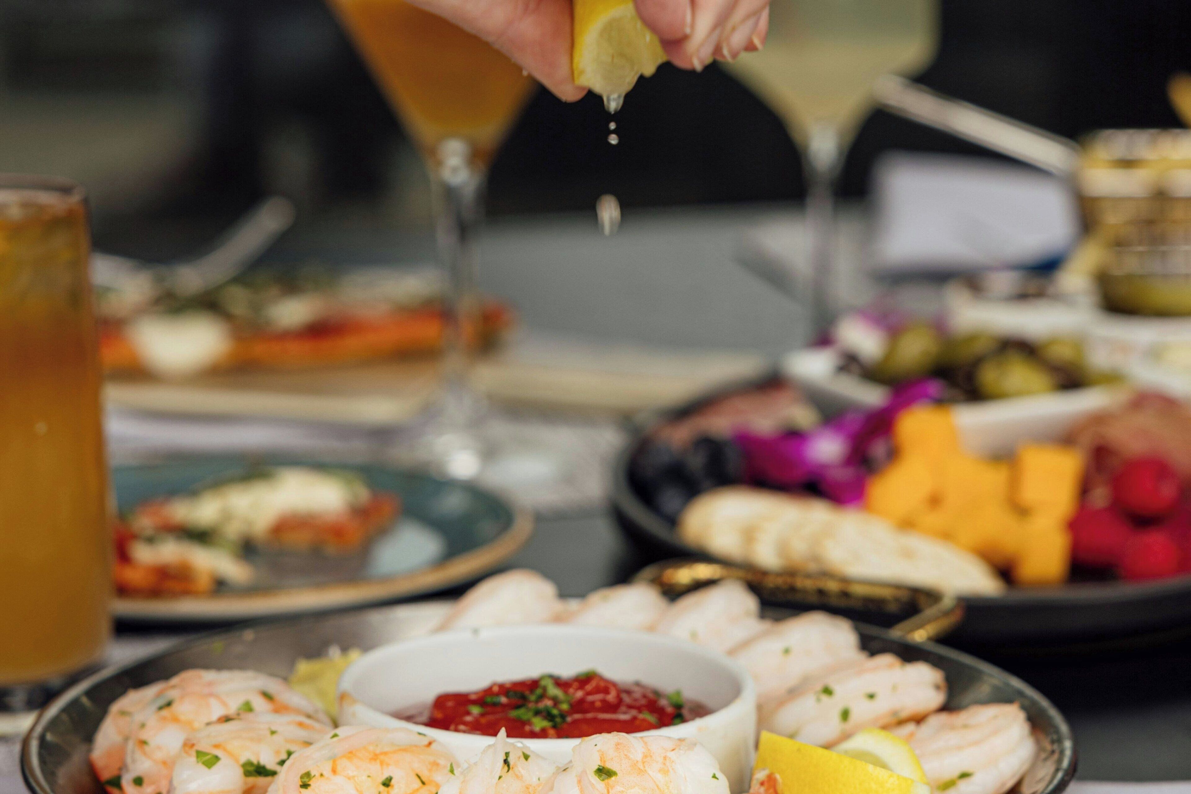 A table with various dishes including shrimp, a bowl of sauce, and other food items.