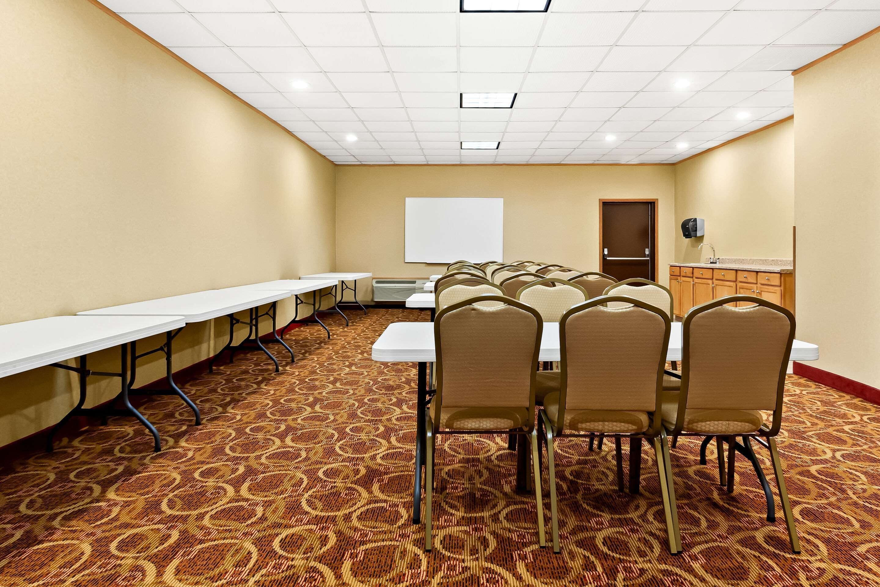 A conference room with a long table, chairs, a whiteboard, and a kitchenette.